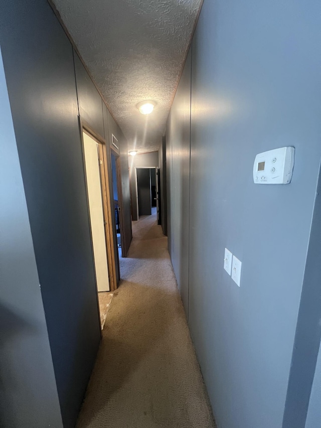 hall with light carpet and a textured ceiling