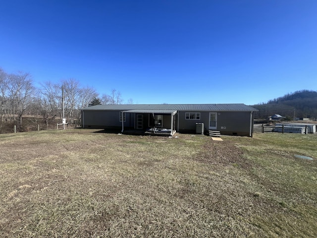 rear view of house with cooling unit and a yard