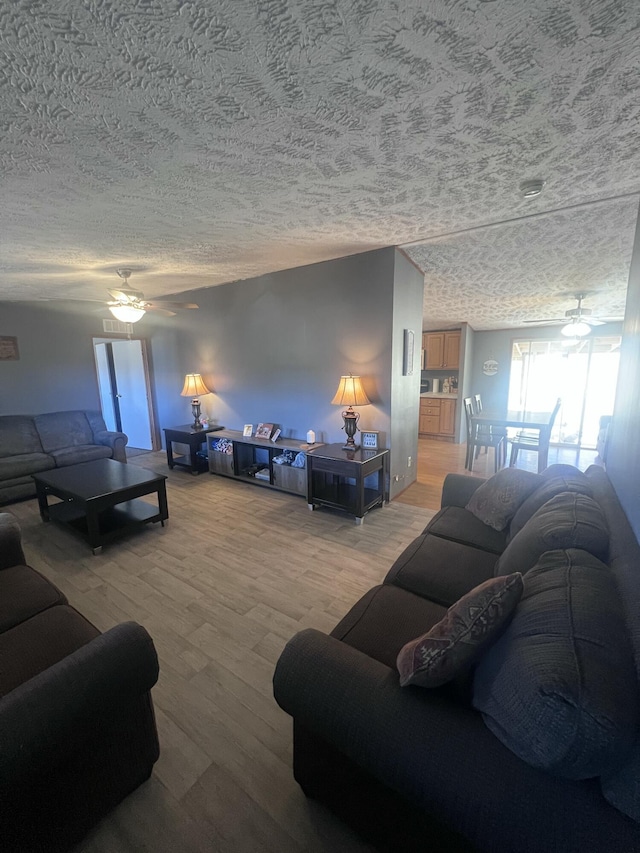 living room featuring hardwood / wood-style floors, a textured ceiling, and ceiling fan