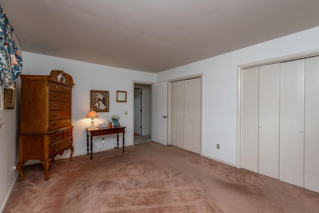 bedroom featuring light colored carpet and two closets