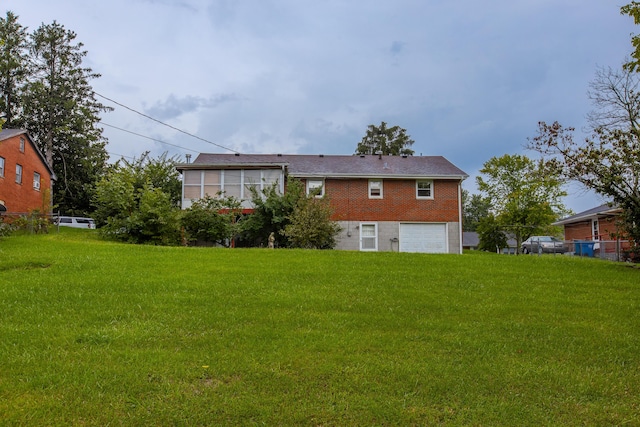 rear view of house with a garage and a yard