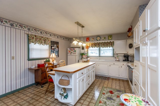 kitchen with decorative light fixtures, white cabinetry, white refrigerator, a center island, and electric stove