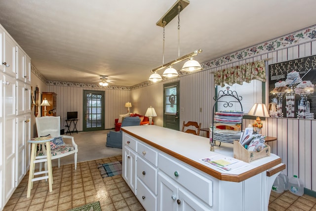 kitchen with white cabinetry, ceiling fan, decorative light fixtures, and a center island