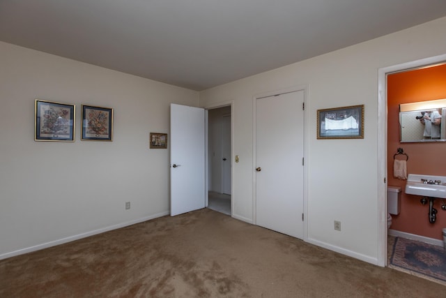 bedroom with ensuite bathroom, carpet, and sink