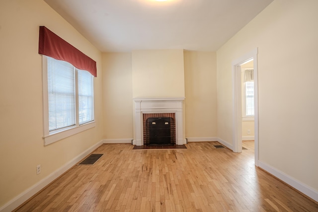 unfurnished living room with a fireplace, light hardwood / wood-style floors, and plenty of natural light