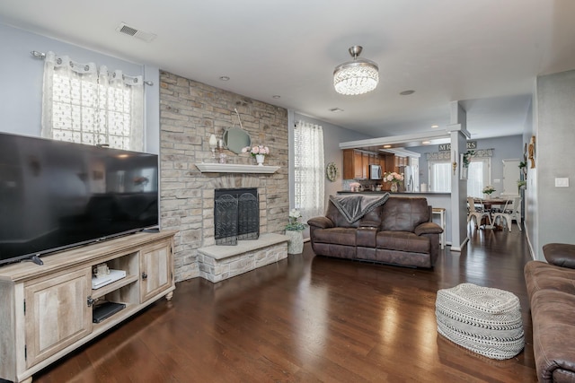 living room with a stone fireplace and dark hardwood / wood-style floors