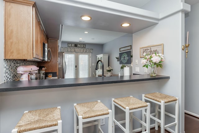 kitchen with sink, stove, backsplash, a kitchen bar, and kitchen peninsula