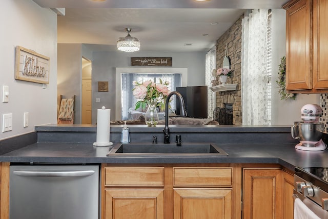 kitchen with stainless steel appliances, a stone fireplace, and sink