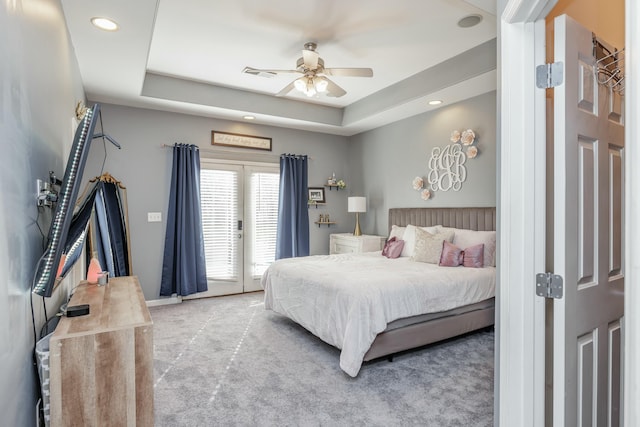 carpeted bedroom with ceiling fan, access to exterior, and a raised ceiling