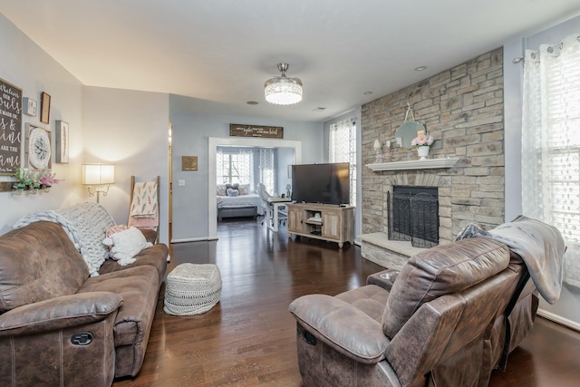 living room with a stone fireplace and dark hardwood / wood-style floors