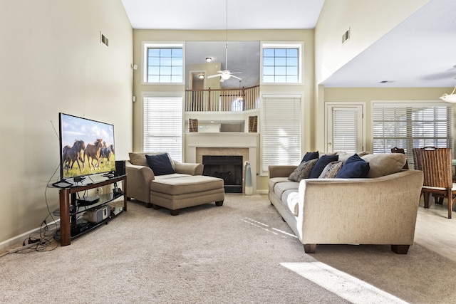 carpeted living room featuring a towering ceiling, plenty of natural light, and ceiling fan