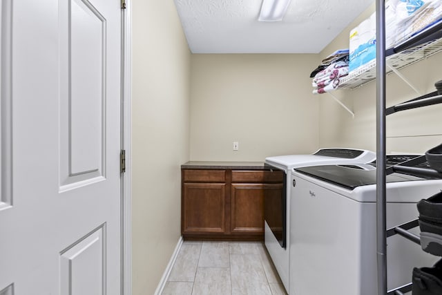 clothes washing area featuring cabinets, independent washer and dryer, and a textured ceiling