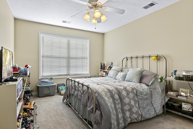 carpeted bedroom featuring ceiling fan and a textured ceiling