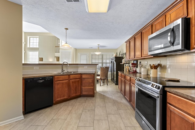 kitchen with pendant lighting, sink, appliances with stainless steel finishes, backsplash, and a textured ceiling