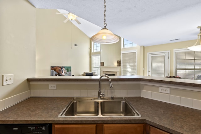 kitchen featuring pendant lighting, sink, dishwasher, a textured ceiling, and vaulted ceiling