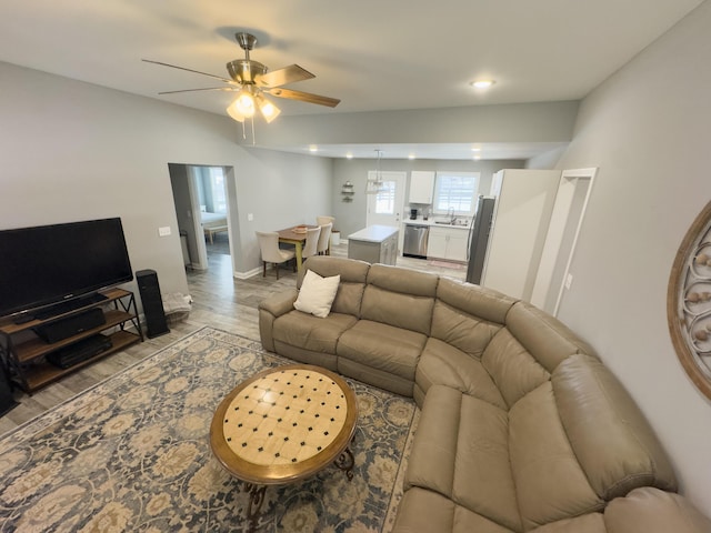 living room featuring ceiling fan, sink, and light wood-type flooring