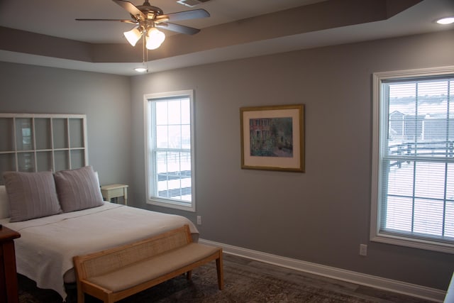 bedroom with hardwood / wood-style flooring, ceiling fan, and a raised ceiling