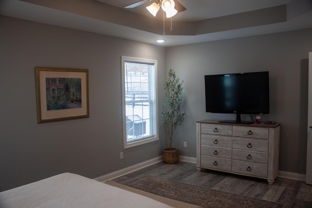 bedroom featuring ceiling fan, dark hardwood / wood-style flooring, and a raised ceiling