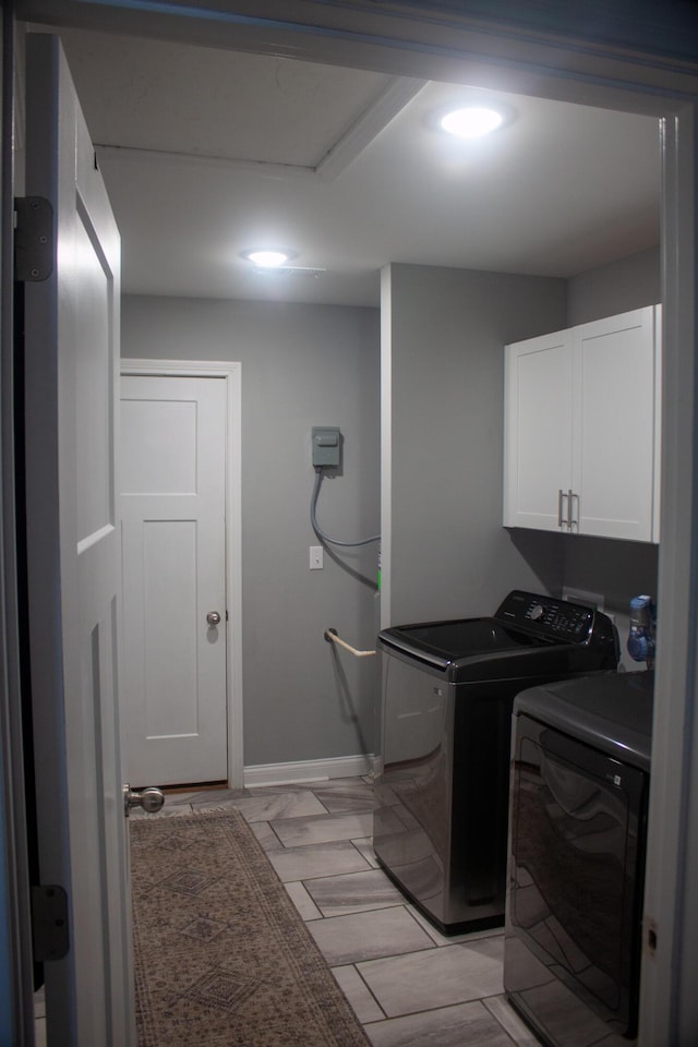 clothes washing area with washer and dryer and cabinets