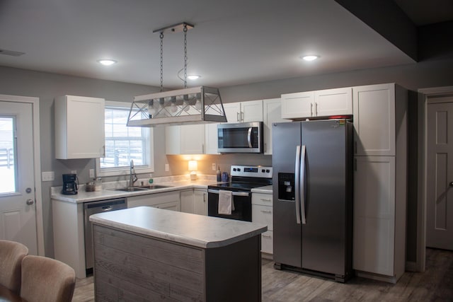 kitchen featuring sink, white cabinetry, decorative light fixtures, a center island, and appliances with stainless steel finishes