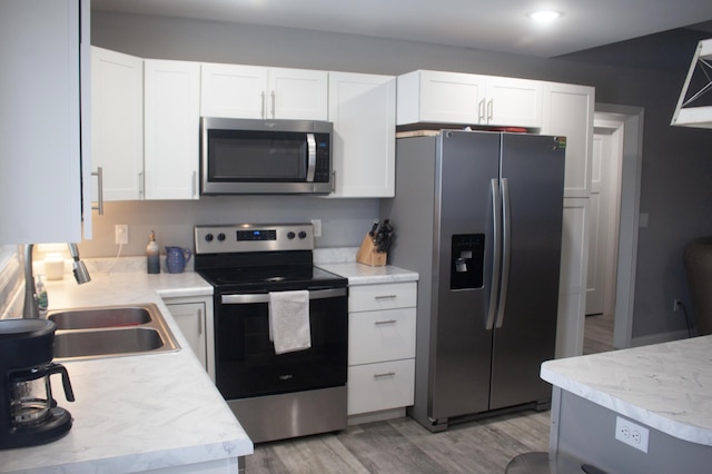 kitchen featuring white cabinetry, appliances with stainless steel finishes, sink, and light hardwood / wood-style flooring