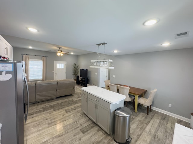 kitchen featuring stainless steel refrigerator, gray cabinetry, hanging light fixtures, light hardwood / wood-style floors, and a kitchen island