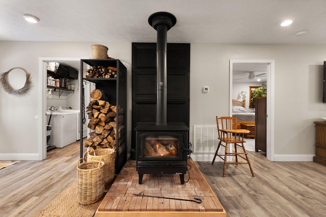 room details with wood-type flooring, washer / dryer, and a wood stove