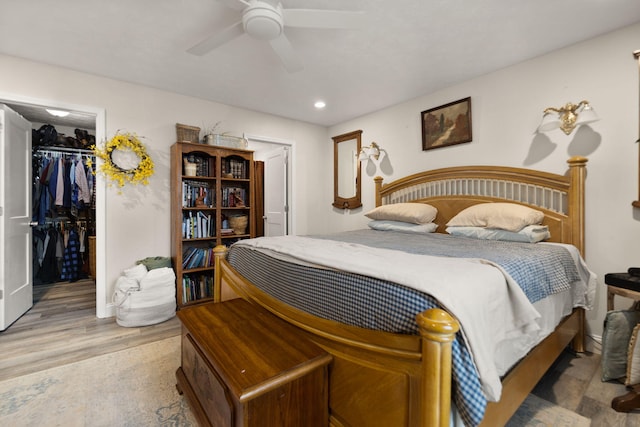 bedroom with wood-type flooring, a walk in closet, ceiling fan, and a closet