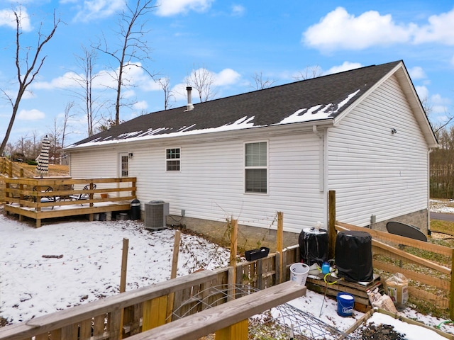 snow covered rear of property with cooling unit and a deck