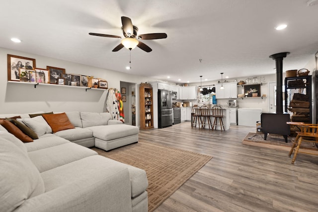 living room featuring light hardwood / wood-style floors, ceiling fan, and a wood stove