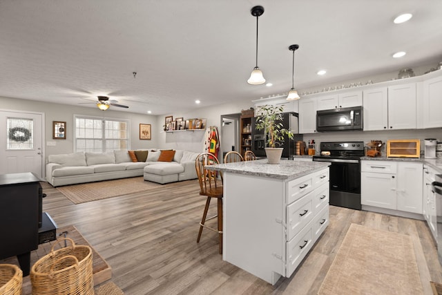 kitchen featuring a kitchen breakfast bar, a center island, range with electric stovetop, white cabinets, and decorative light fixtures