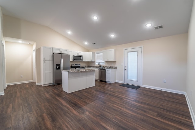 kitchen featuring vaulted ceiling, white cabinets, a center island, light stone counters, and stainless steel appliances