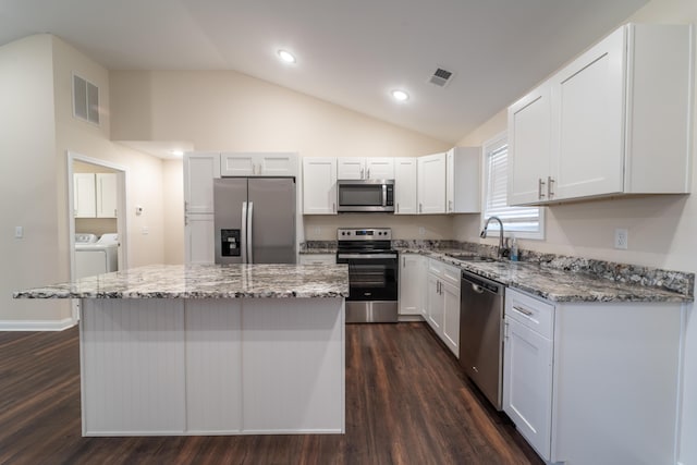 kitchen with stainless steel appliances, washing machine and dryer, and white cabinets