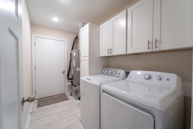 laundry room with cabinets, separate washer and dryer, and water heater