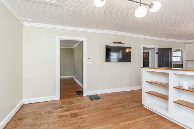 spare room featuring ornamental molding and light wood-type flooring