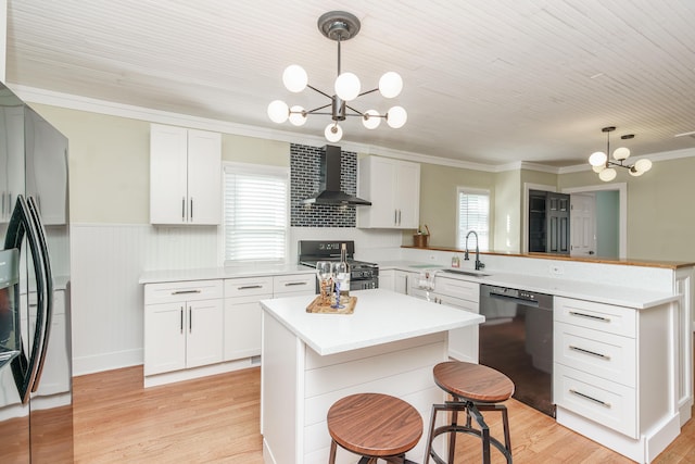 kitchen featuring pendant lighting, white cabinets, wall chimney exhaust hood, and black appliances