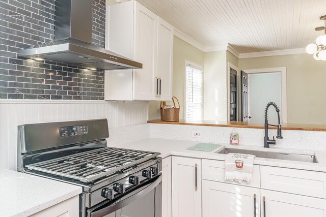 kitchen featuring sink, white cabinetry, black appliances, pendant lighting, and wall chimney range hood