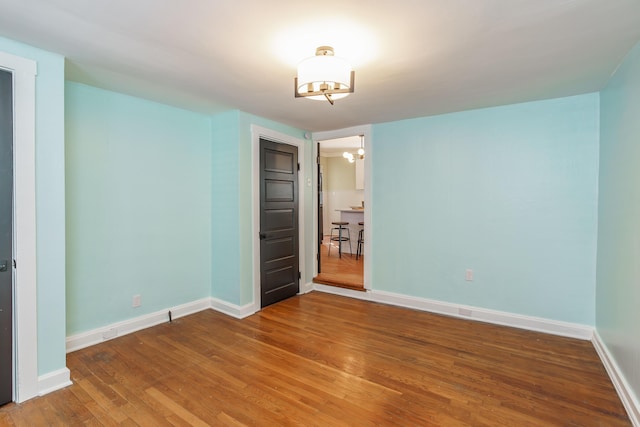 unfurnished bedroom with hardwood / wood-style flooring and a chandelier