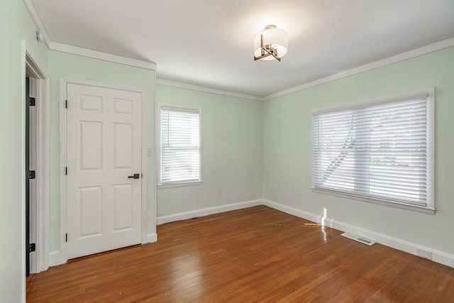 empty room with ornamental molding and wood-type flooring