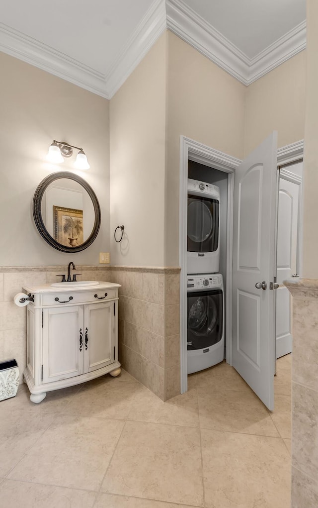 bathroom featuring stacked washing maching and dryer, tile walls, vanity, and crown molding