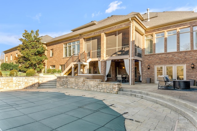 back of property with a covered pool and a patio area