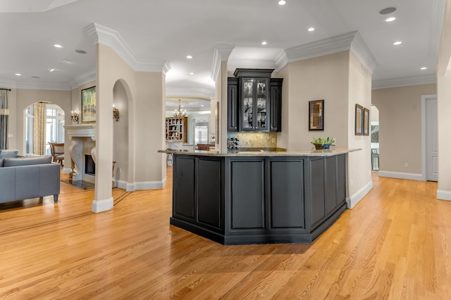 bar featuring tasteful backsplash, crown molding, light hardwood / wood-style floors, and an inviting chandelier