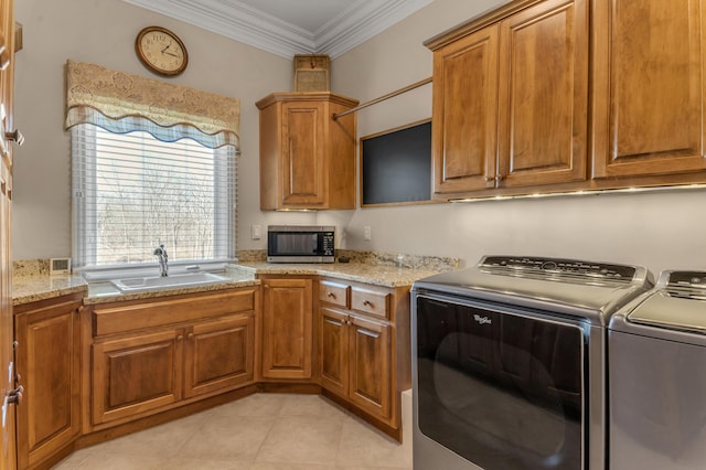 kitchen with ornamental molding, light stone countertops, sink, and washing machine and clothes dryer