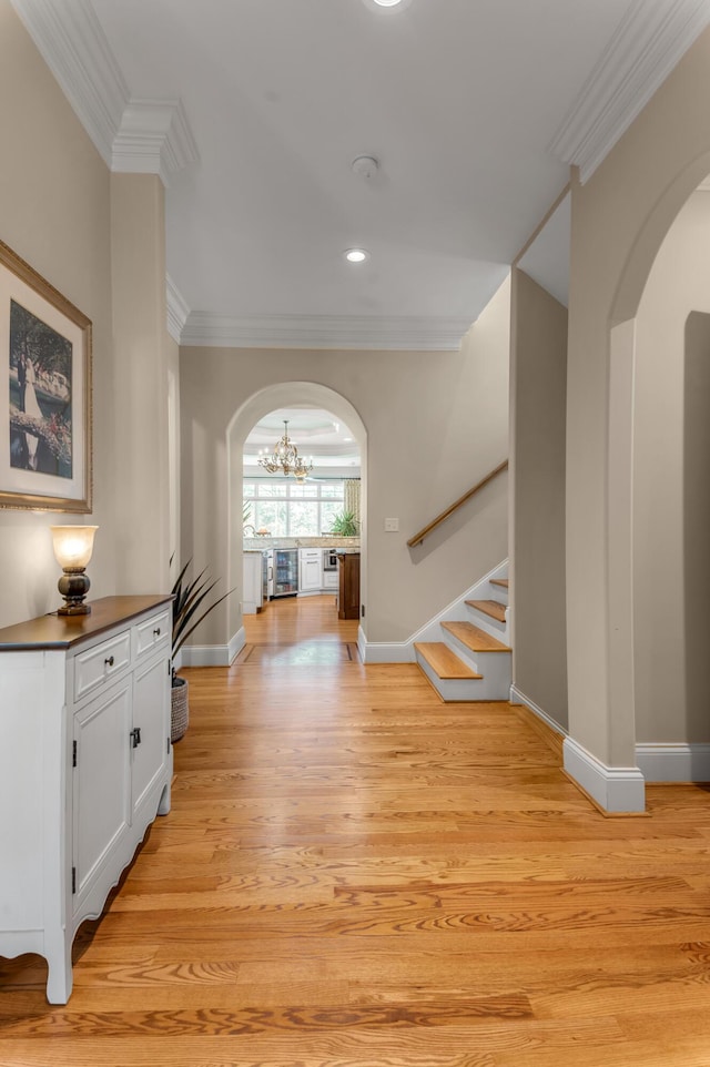 hall with crown molding, an inviting chandelier, and light hardwood / wood-style floors