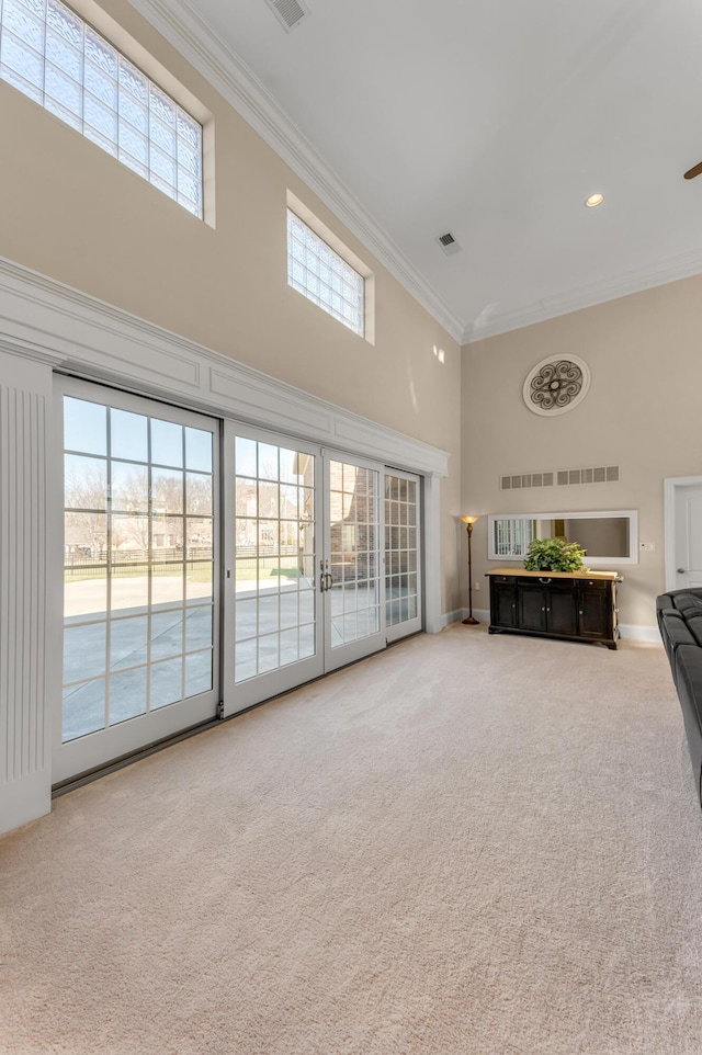 unfurnished living room featuring crown molding, carpet, french doors, and a towering ceiling