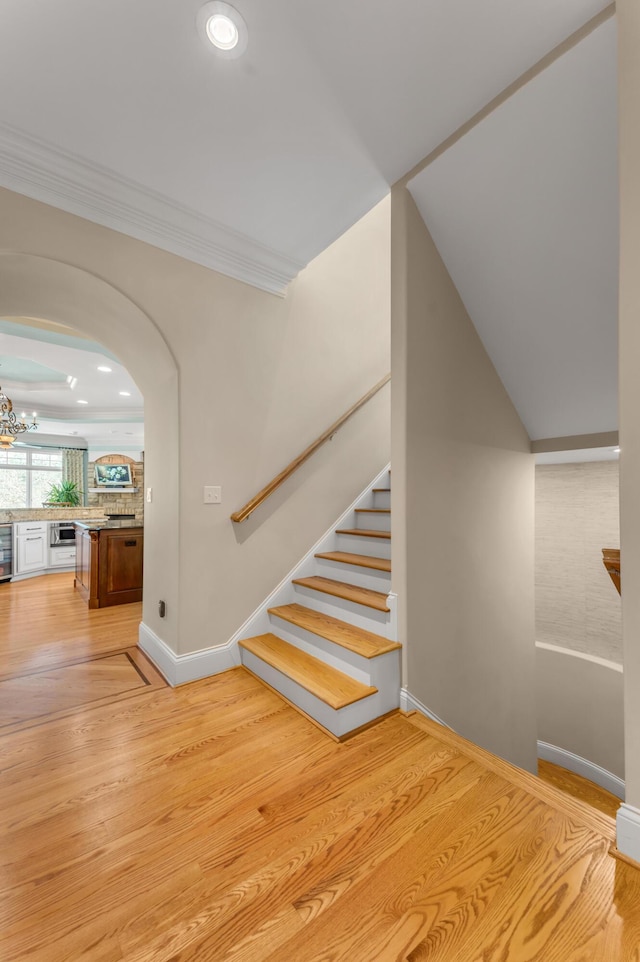 stairs featuring ornamental molding, hardwood / wood-style floors, and a notable chandelier