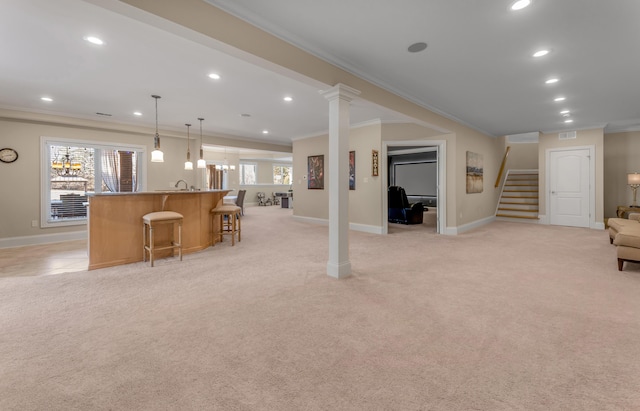 carpeted living room featuring bar, crown molding, a wealth of natural light, and decorative columns