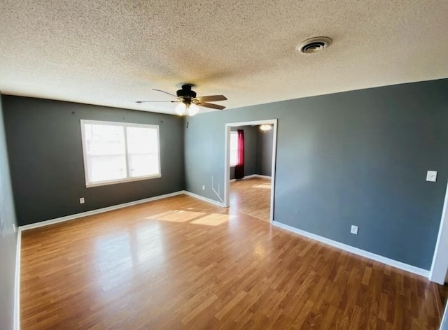 unfurnished room with ceiling fan, light hardwood / wood-style flooring, and a textured ceiling