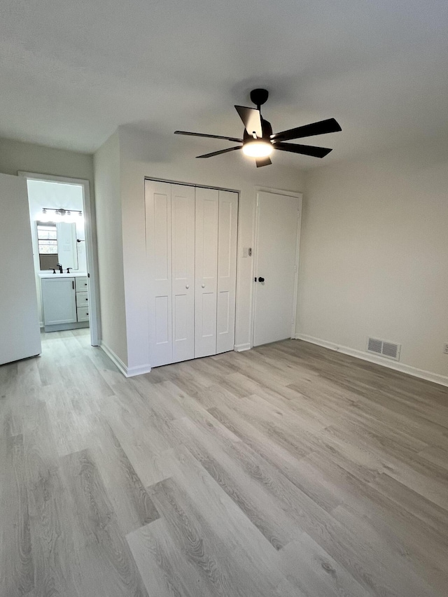 unfurnished bedroom featuring a closet, white fridge, ceiling fan, and light hardwood / wood-style flooring