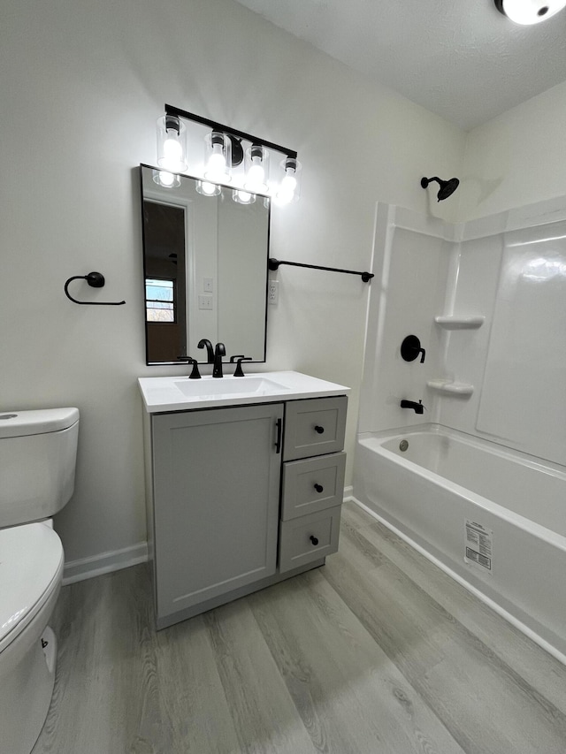 full bathroom featuring vanity, hardwood / wood-style floors, washtub / shower combination, and toilet